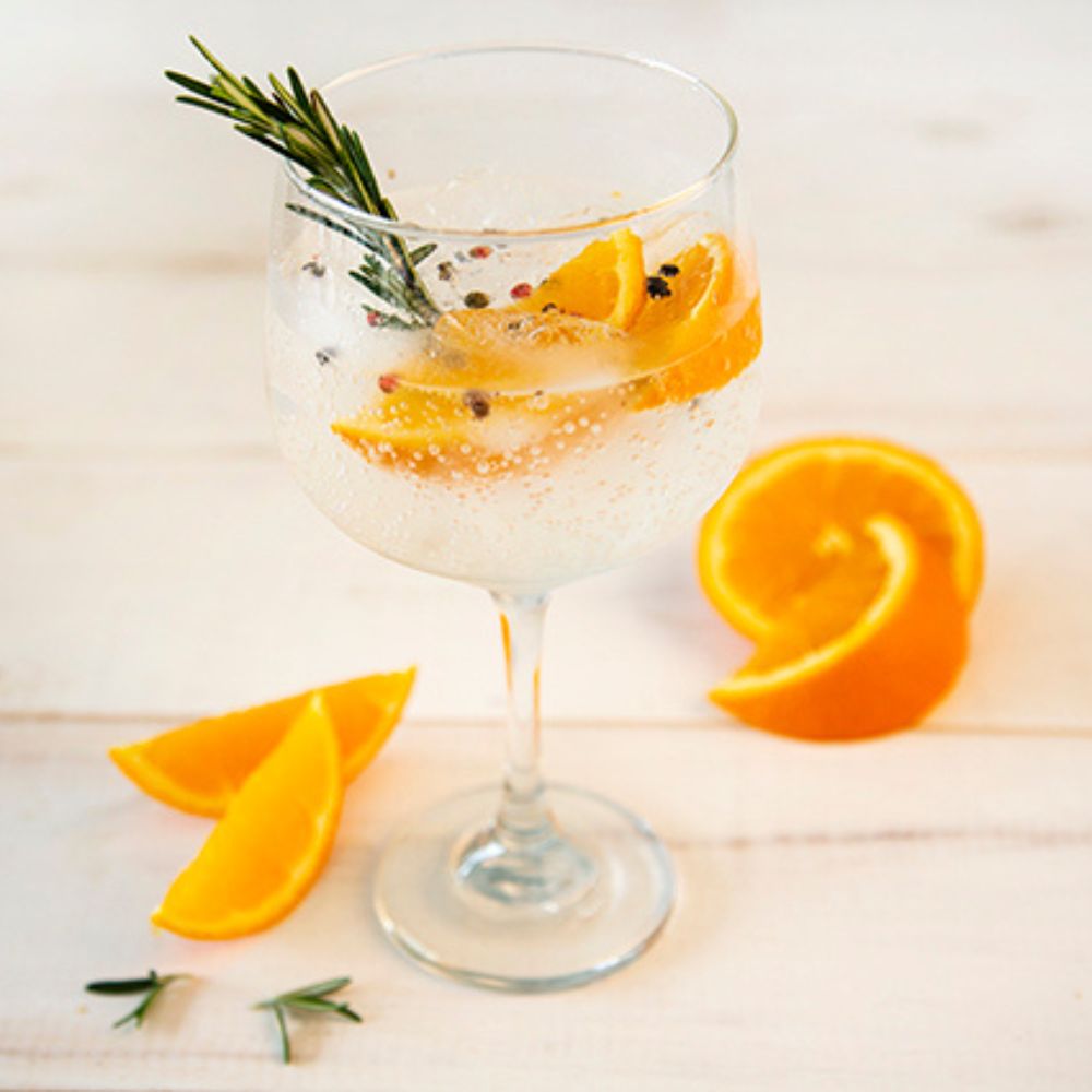 Copa de vidrio para cóctel con bebida y rodajas de naranja