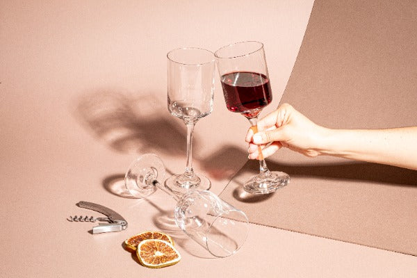 Persona sosteniendo copa para vino, alrededor copas vacías. Colección Río