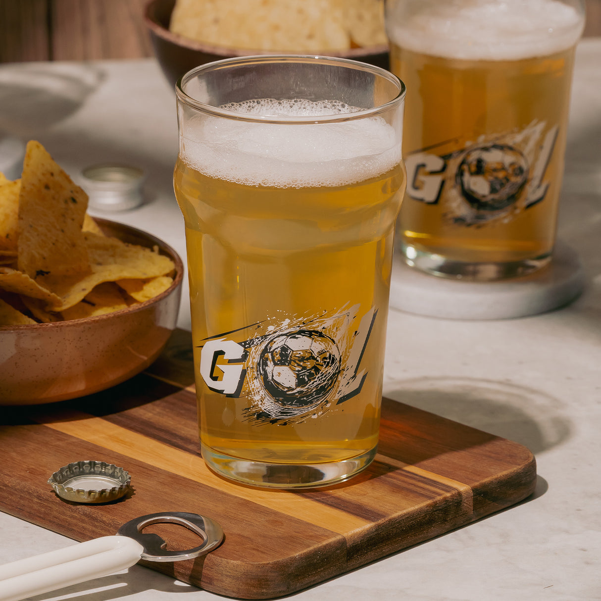 Cerveza fría servida en vasos britain fútbol acompañado con chips en superficie de madera