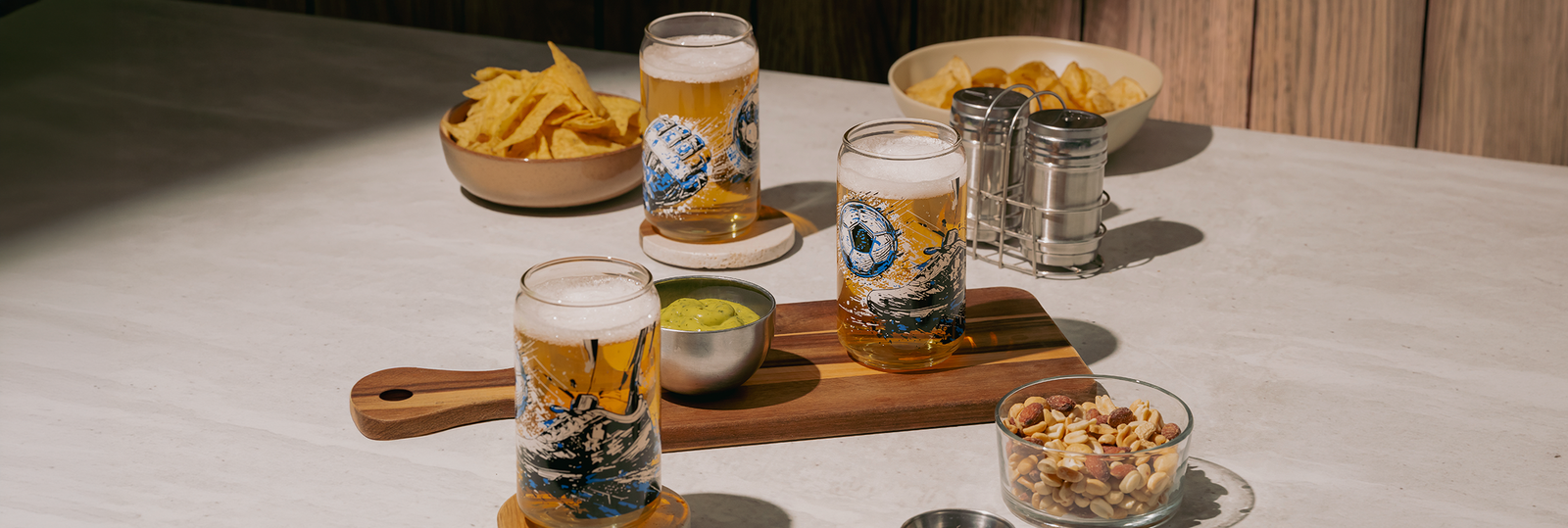 Vasos de vidrio con diseño de balón de fútbol, snacks servidos en mesa