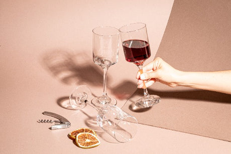 Persona sosteniendo copa para vino, alrededor copas vacías. Colección Río