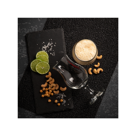 Dos copas cerveceras pragas sobre superficie decorada con limones y nueces