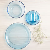 Cuatro piezas de la vajilla stylo color azul sobre mesa: mug, platillo, plato hondo, plato pando