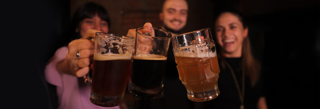 Tres personas brindando con jarrón cervecero
